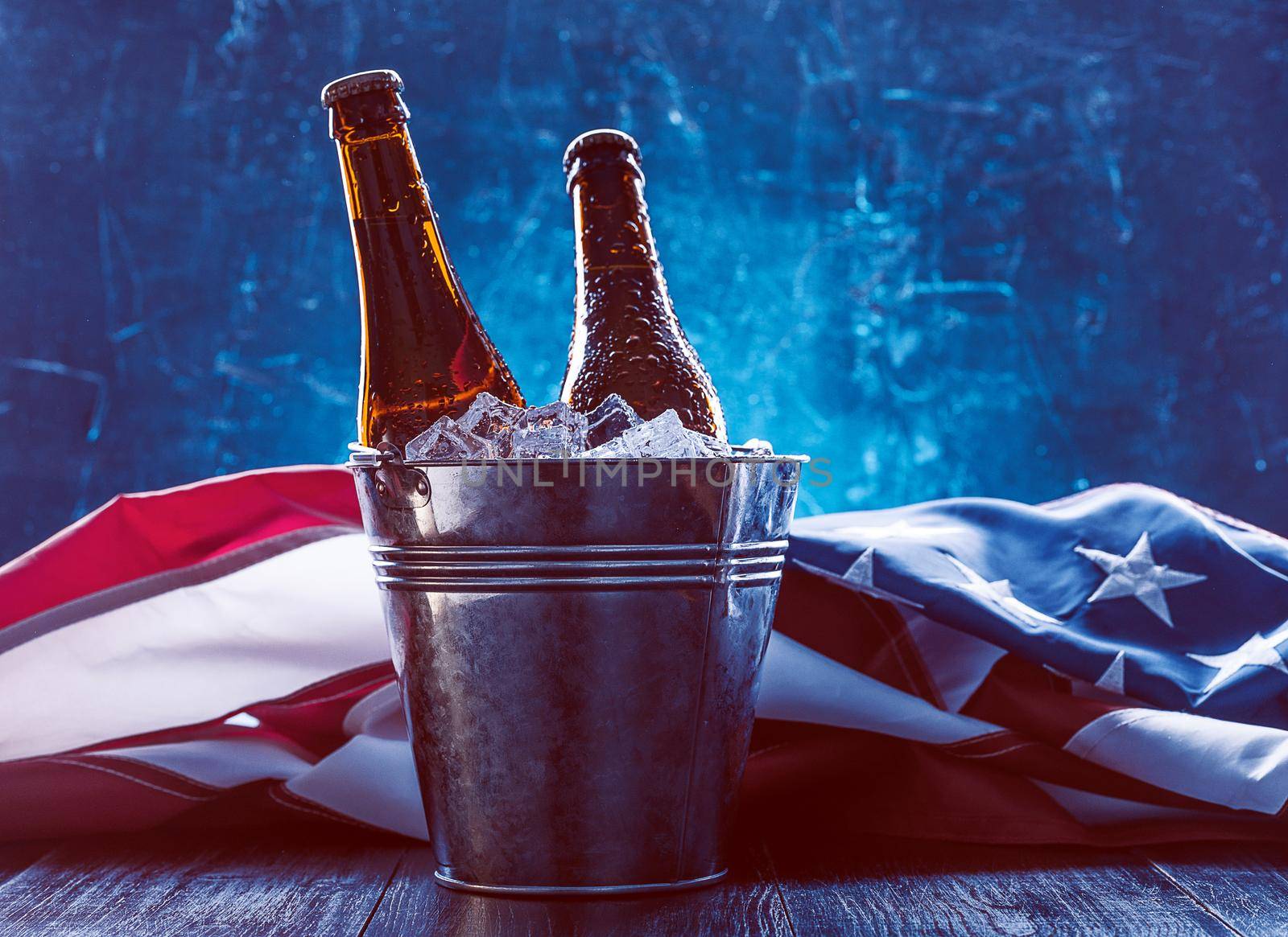 two bottles of beer in an ice bucket with the American flag lying nearby. Independence Day celebration concept