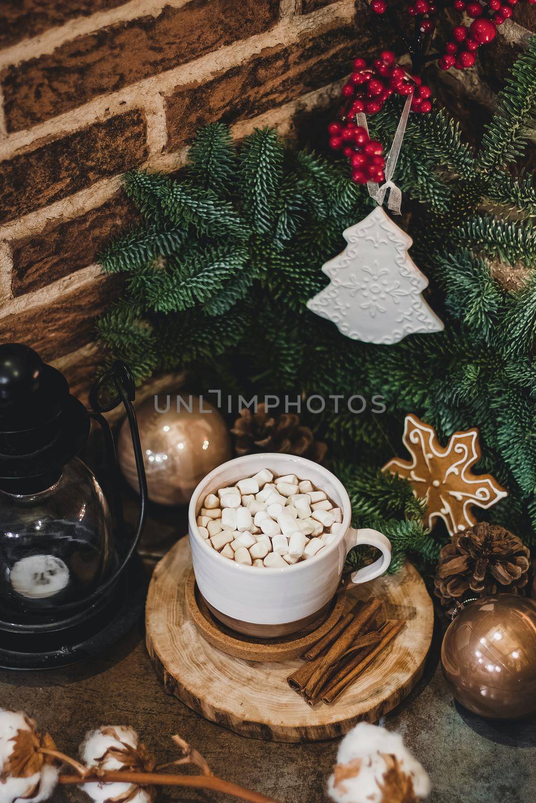 Christmas hot chocolate with mini marshmellows in an old ceramic mug with candles on a wooden background.