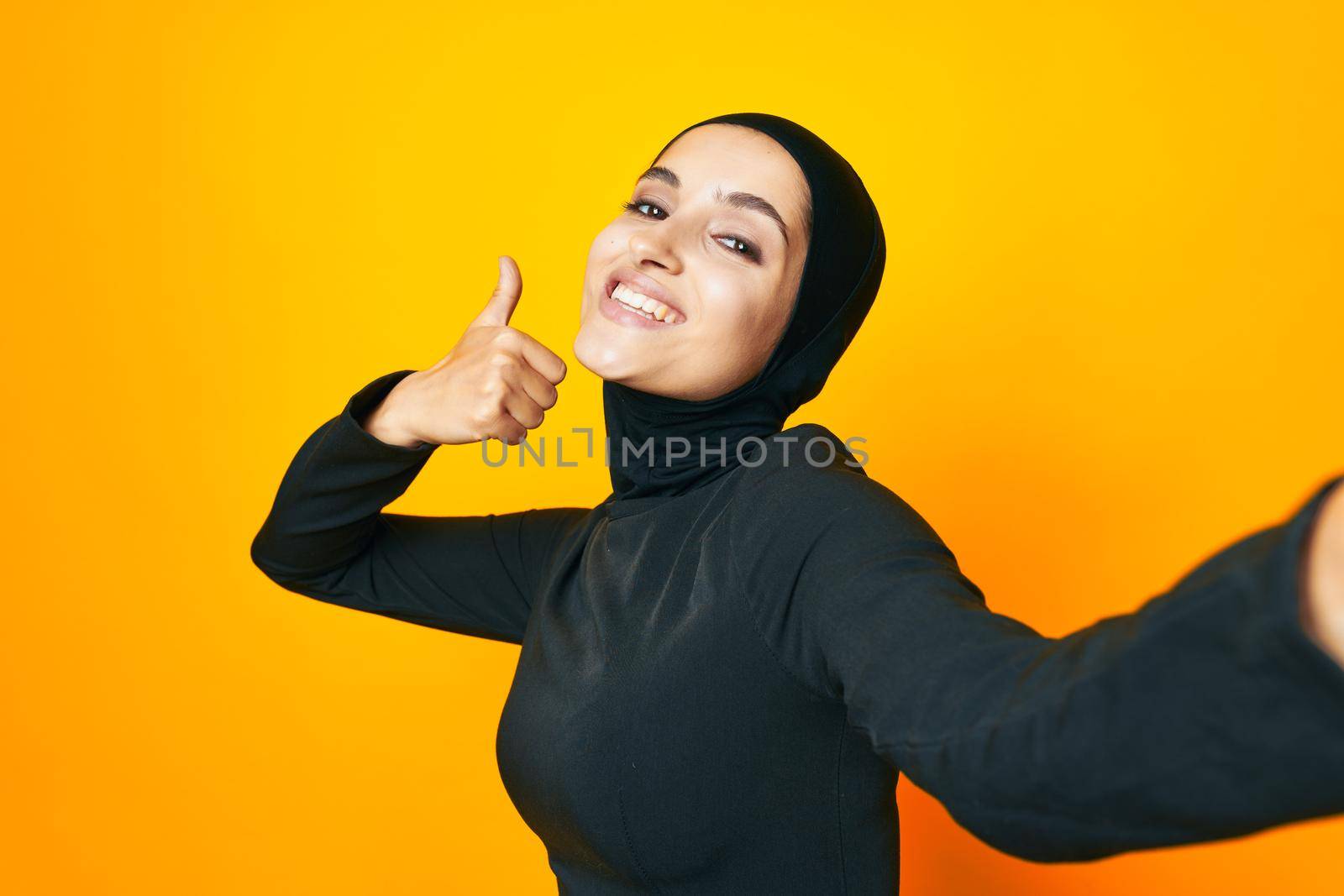 cheerful woman in black hijab posing fashion hand gesture isolated background by Vichizh