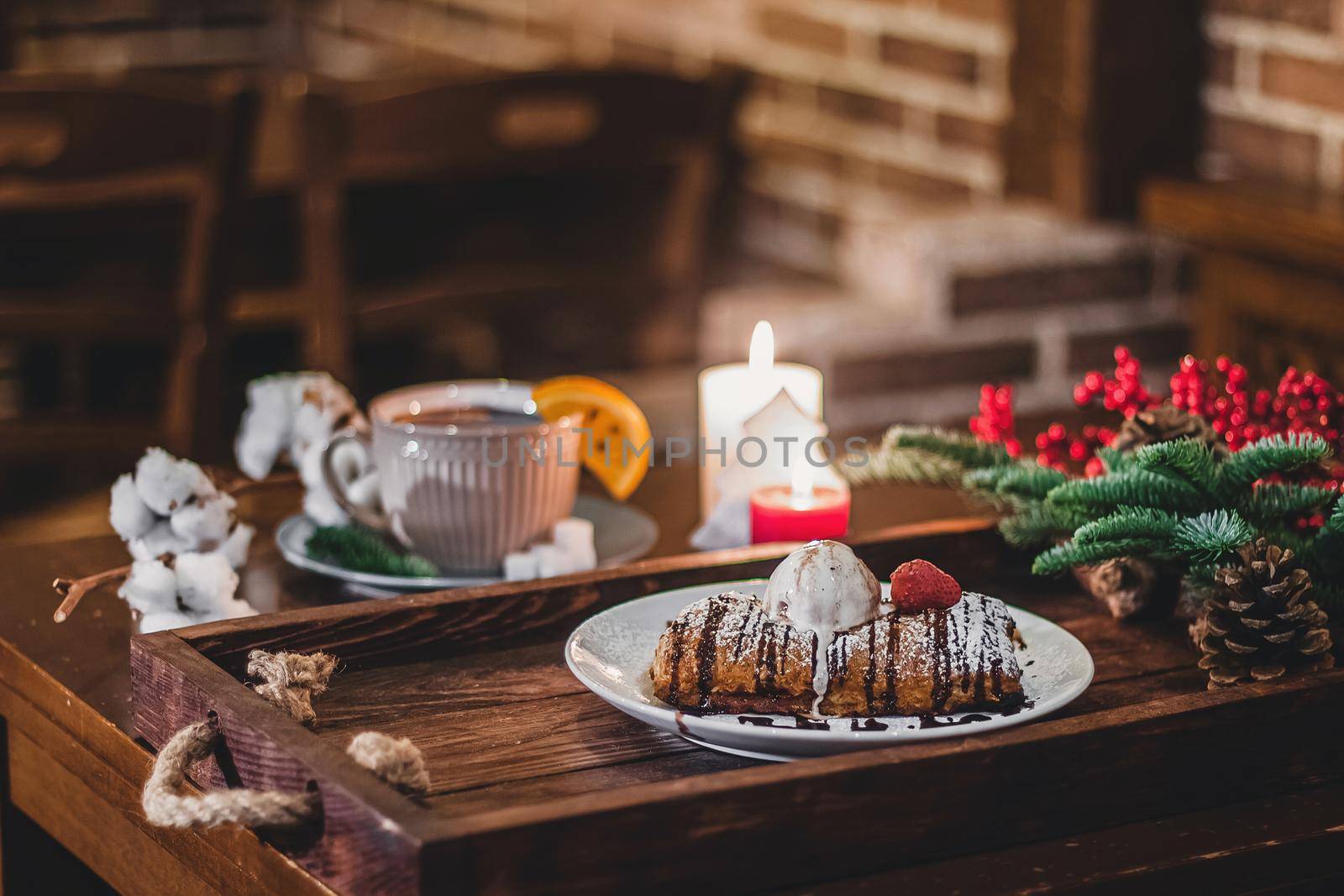 Closeup of a strudel with a strawberry on a Christmas plate near bamboo branch. Christmas breakfast on a wooden table