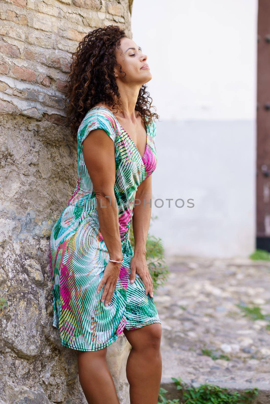 Beautiful brunette middle-aged woman in her 40s wearing spring colorful dress outdoors.