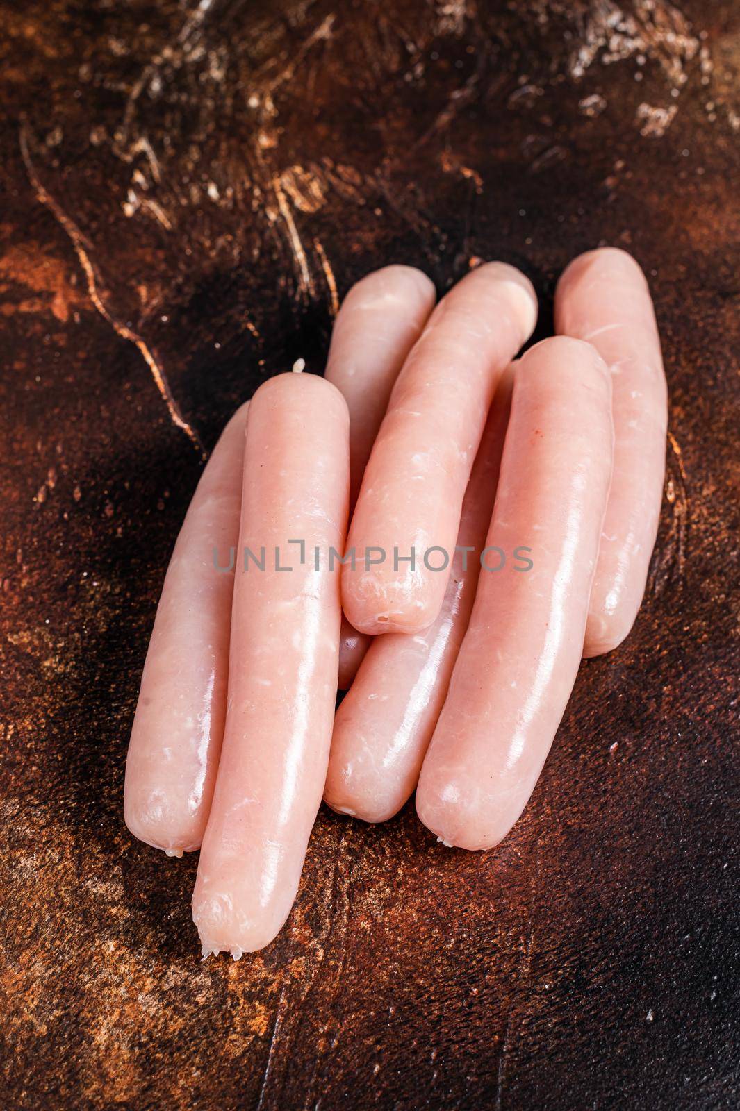 Raw chicken and turkey meat sausages on butcher table. Dark background. Top view.