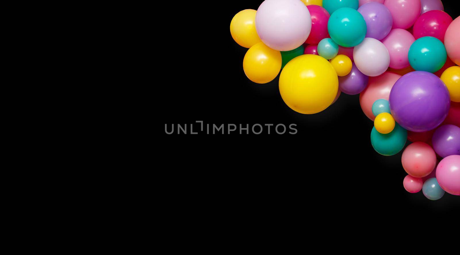 A group of colorful party balloons on a black background with copy space