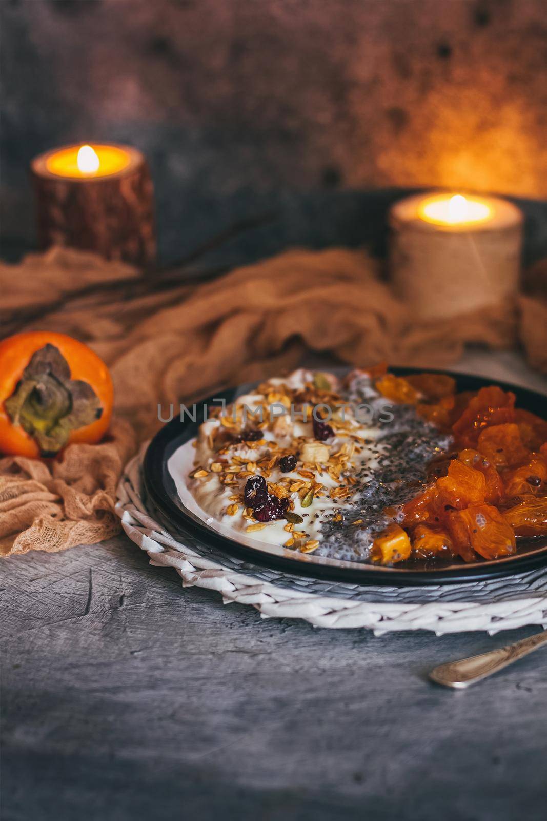 Healthy breakfast concept. Oatmeal granola with yogurt, dried fruit, seeds, honey, persimmon in bowl over grey concrete background. Allergy-friendly, gluten free concept by mmp1206