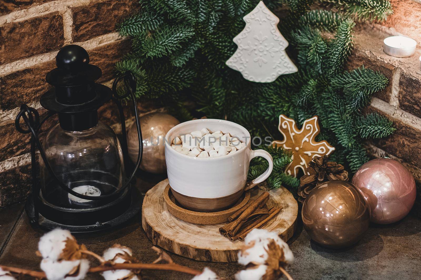 Christmas hot chocolate with mini marshmellows in an old ceramic mug with candles on a wooden background.