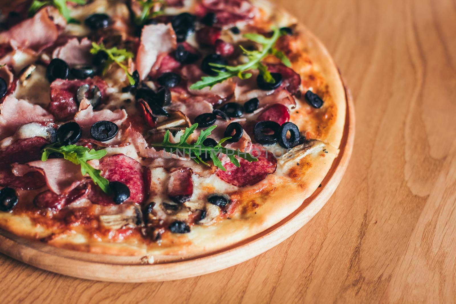 Delicious italian pizza served on wooden table on the pizza board.