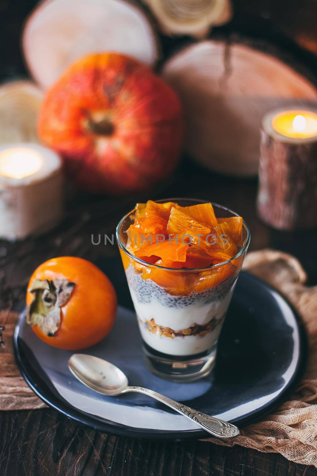 Delicious breakfast: chia seed pudding and persimmon close up in a glass on the table. vertical.