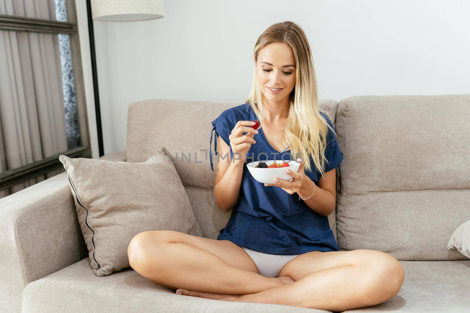 Caucasian girl in casual clothes eating an vegan appetizer with nuts, raspberries and blackberries. Concept of healthy diet.