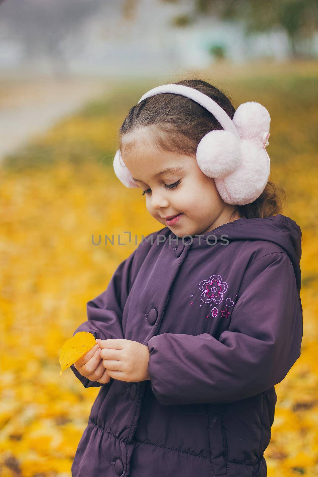 Adorable funny naughty little girl in the park on beautiful autumn day.