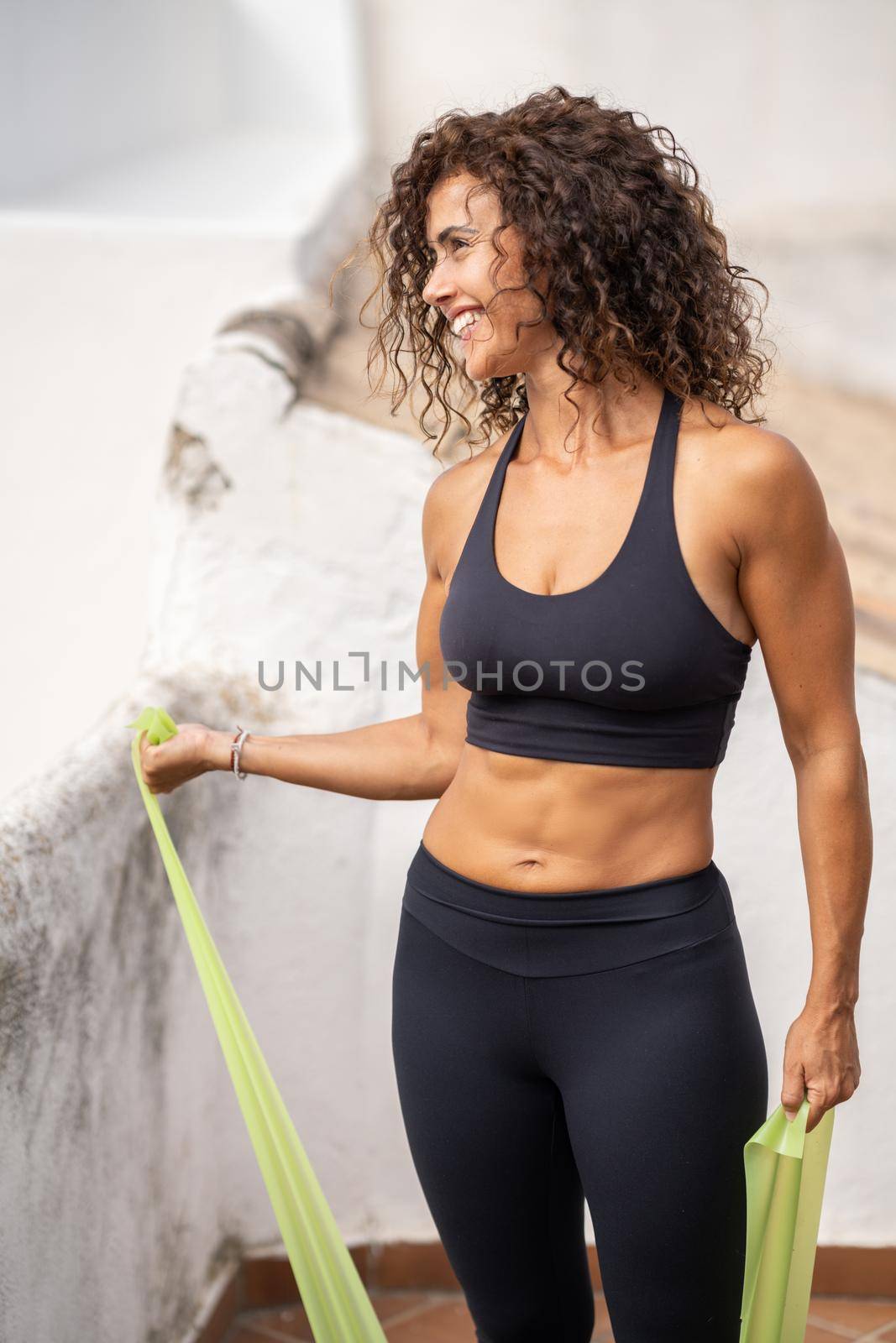 Middle-aged woman with fitness body working out on the terrace of her house by javiindy