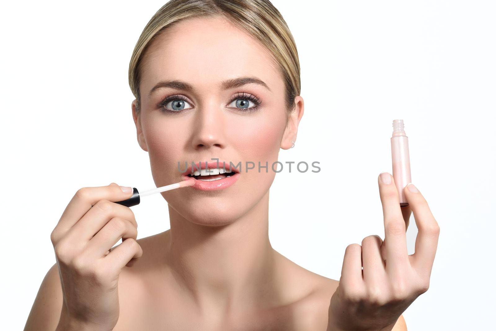 Beautiful woman with clean fresh skin applying pink lip gloss. Skin care face. Cosmetology. Blonde girl with blue eyes.