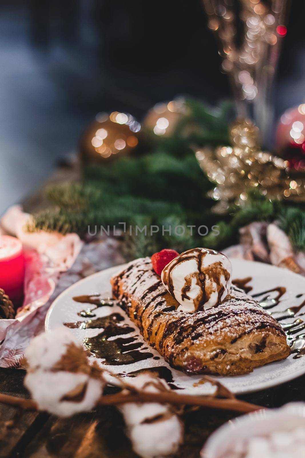 Closeup of a strudel with a strawberry on a Christmas plate near bamboo branch. Christmas breakfast on a wooden table. by mmp1206