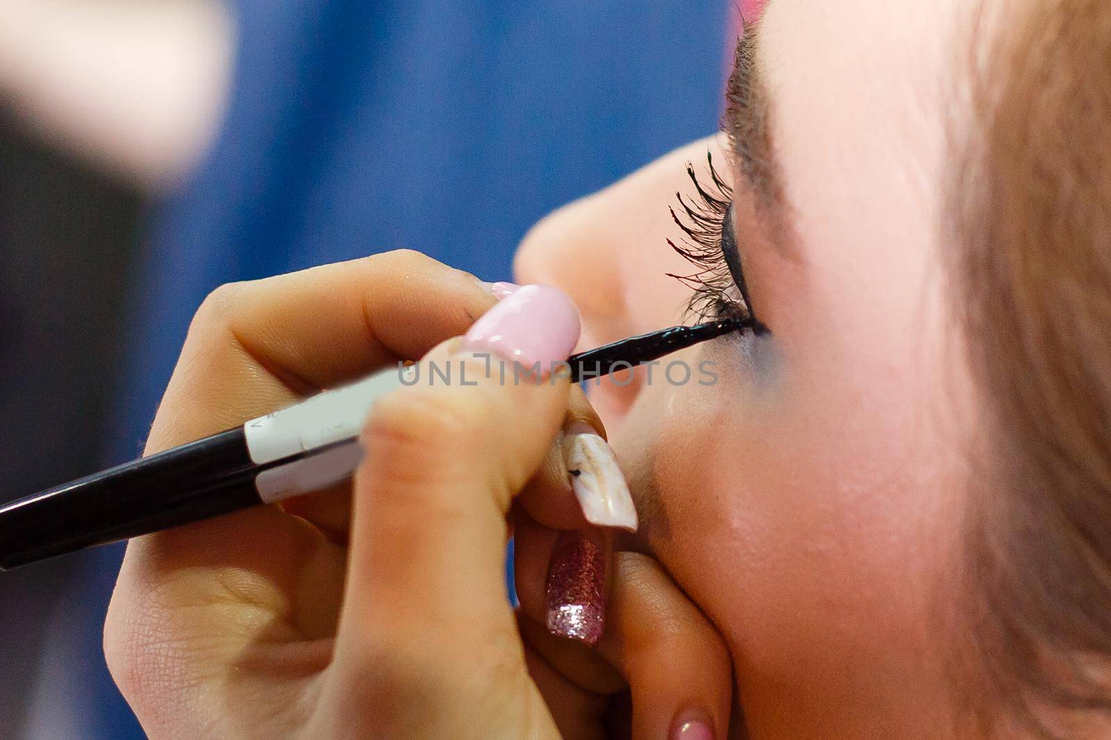 Applying eyeliner and mascara. Make-up for a woman with long curled eyelashes