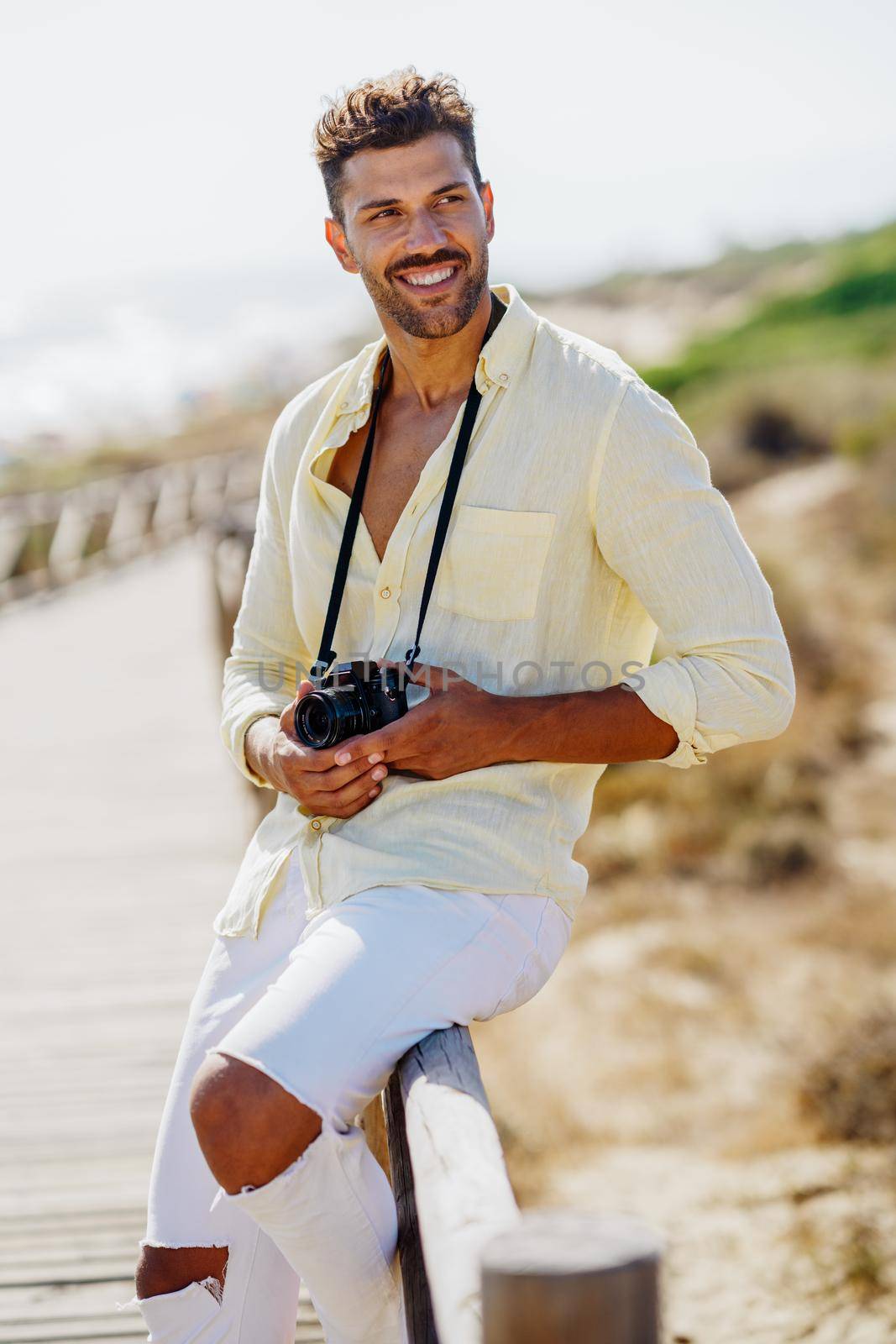 Smiling man photographing in a coastal area with an SLR camera