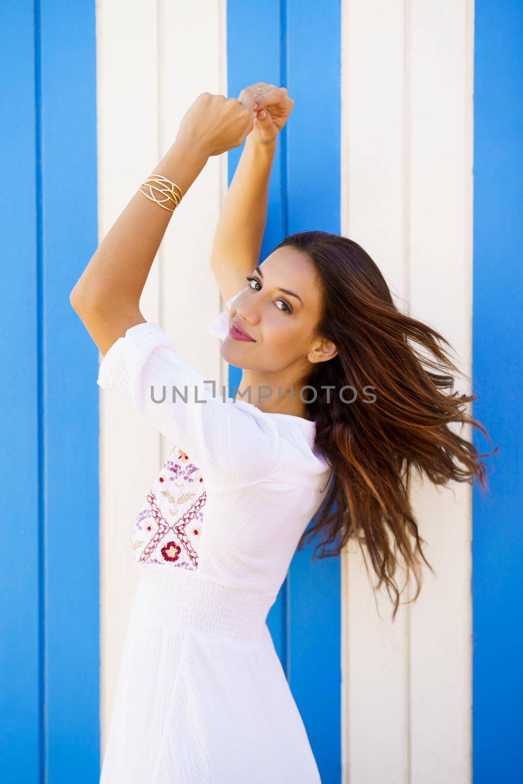 Young woman, fashion model, posing in front of a beach booth looking at the camera.