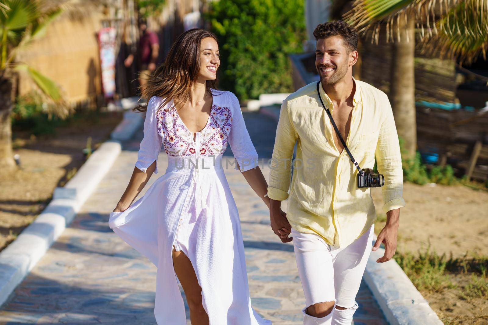 Loving couple walking along a wooden path towards the beach in a coastal area. by javiindy