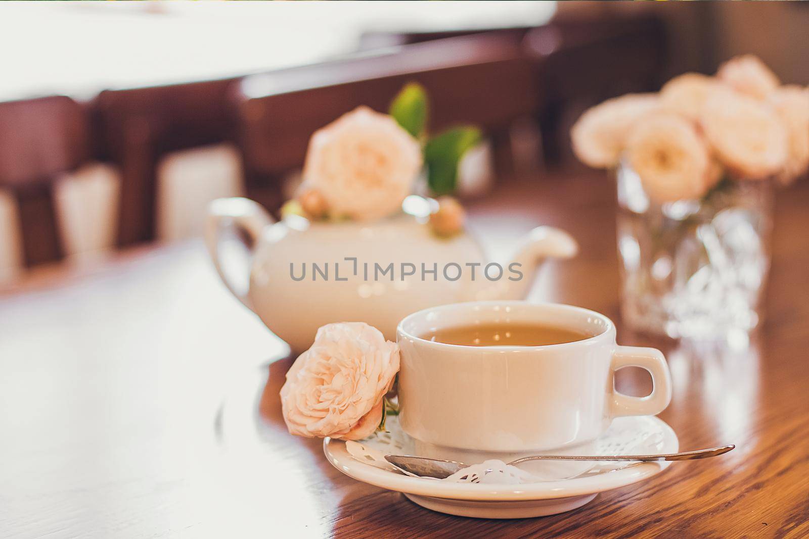 Beautiful fresh roses near a cup of tea and a in pastel tones romantic mood.