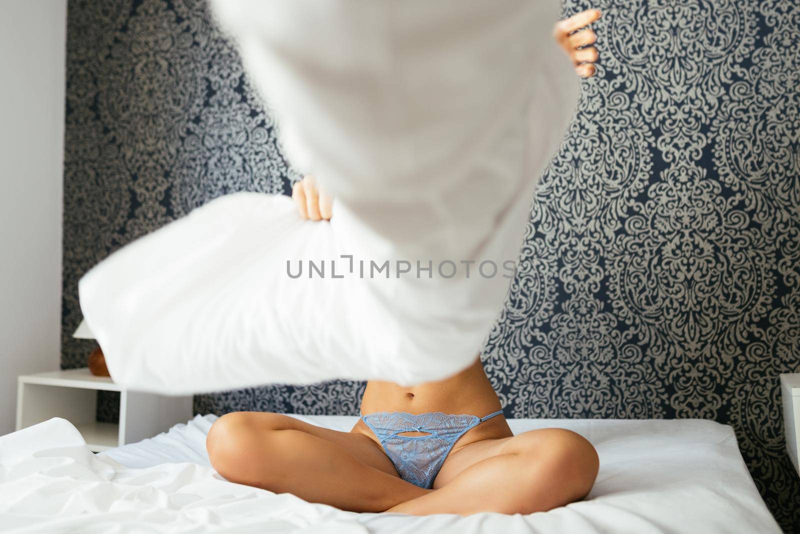 Unrecognizable girl in blue lingerie playing with her pillow on the bed by javiindy