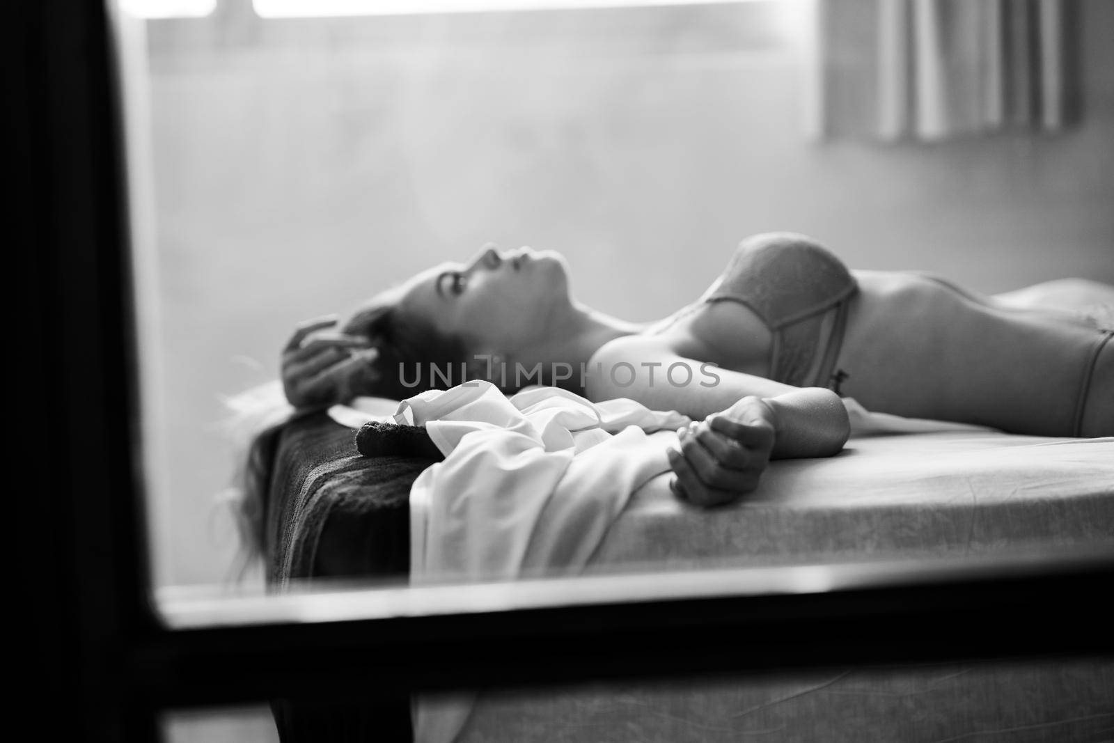 Defocused woman in lingerie lying on the bed. Black and white photograph with added art noise.
