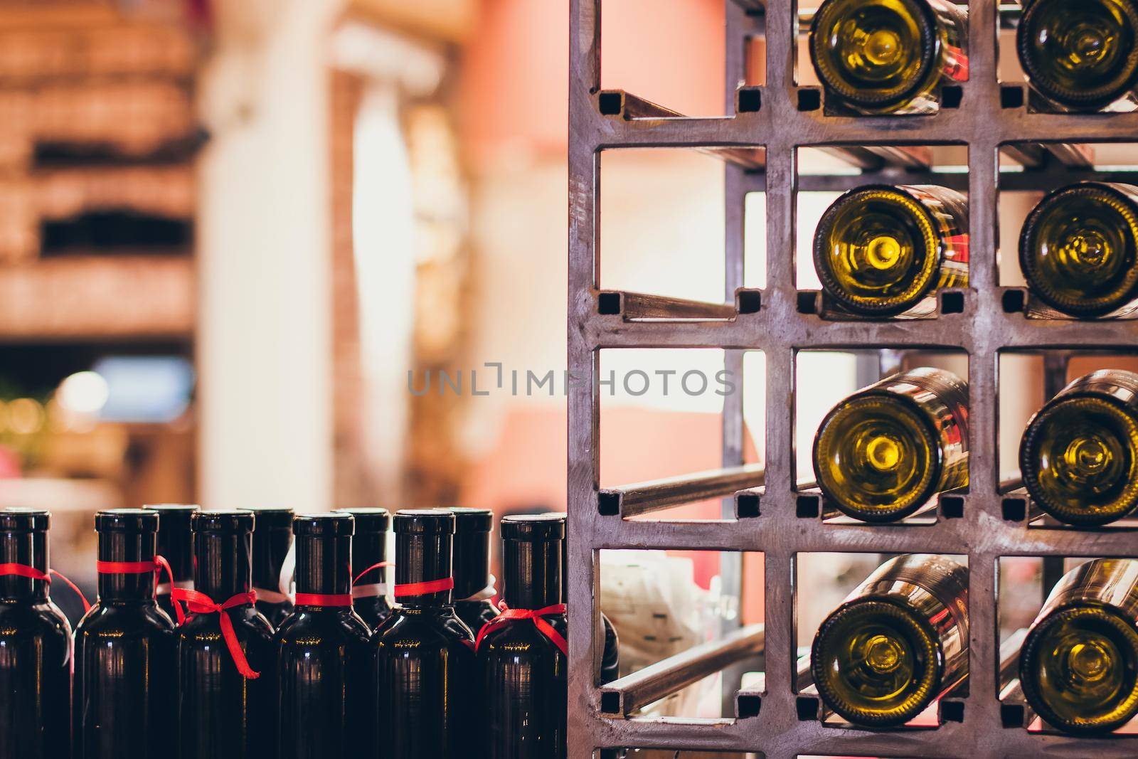 Closeup shot of wine shelf. Bottles lay over straw. Wine cellar