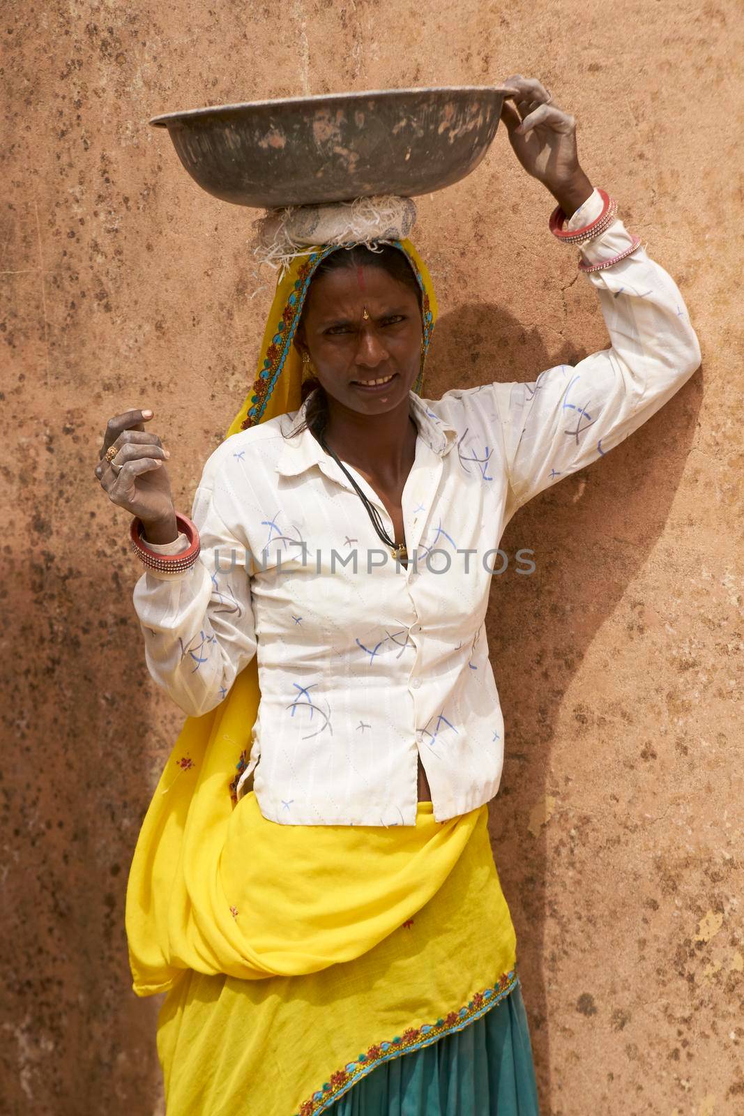 JAIPUR, RAJASTHAN, INDIA - JULY 30, 2008: Female laborers transporting water and plaster in bowls carried on the head during the restoration of a palace inside Amber Fort in Jaipur, Rajasthan, India.