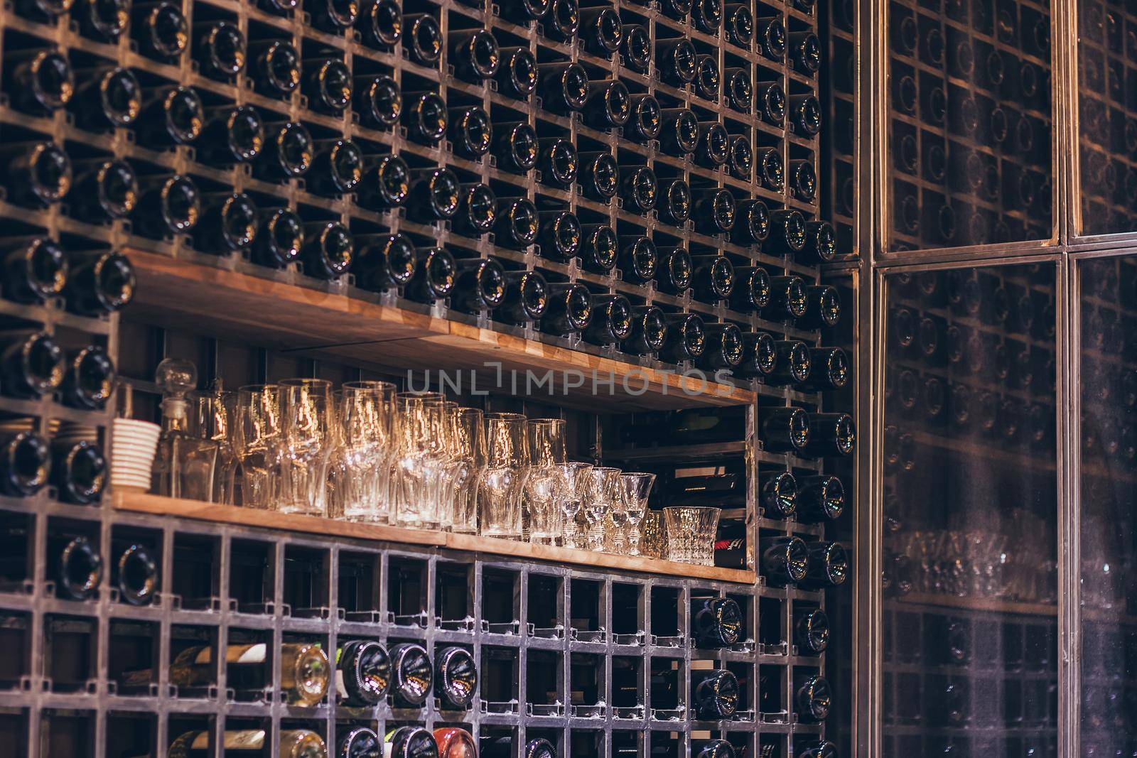 Closeup shot of wine shelf. Bottles lay over straw. Wine cellar