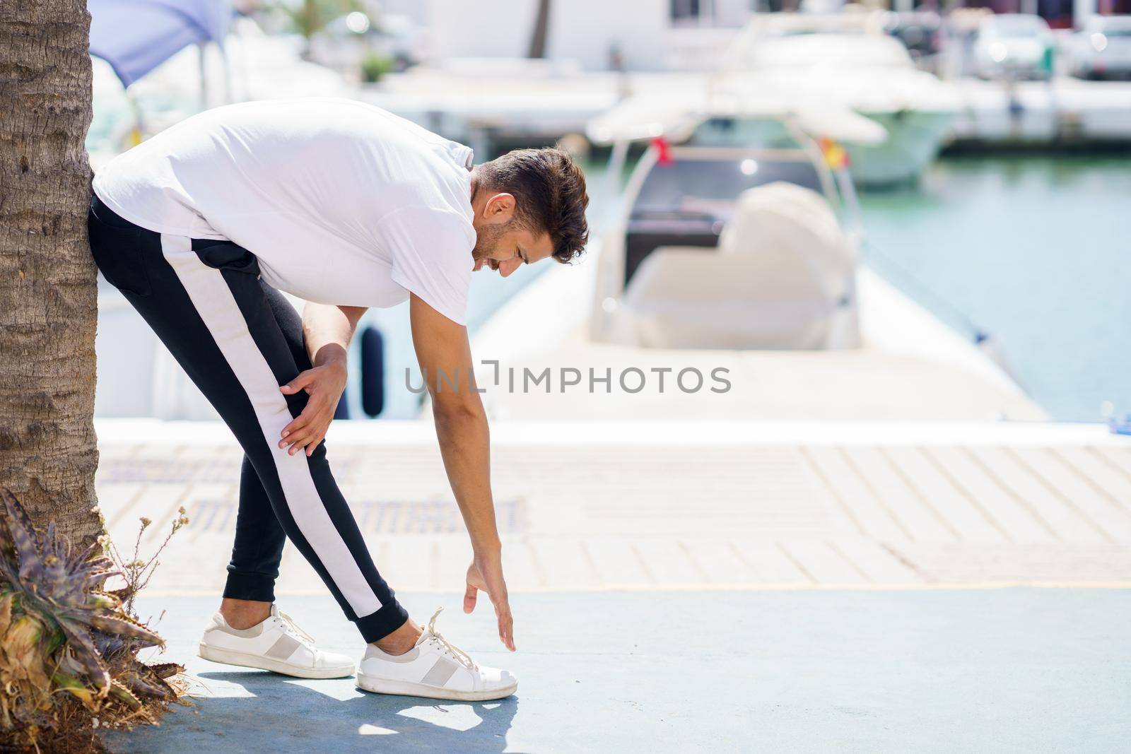 Young man stretching after exercise in a harbour