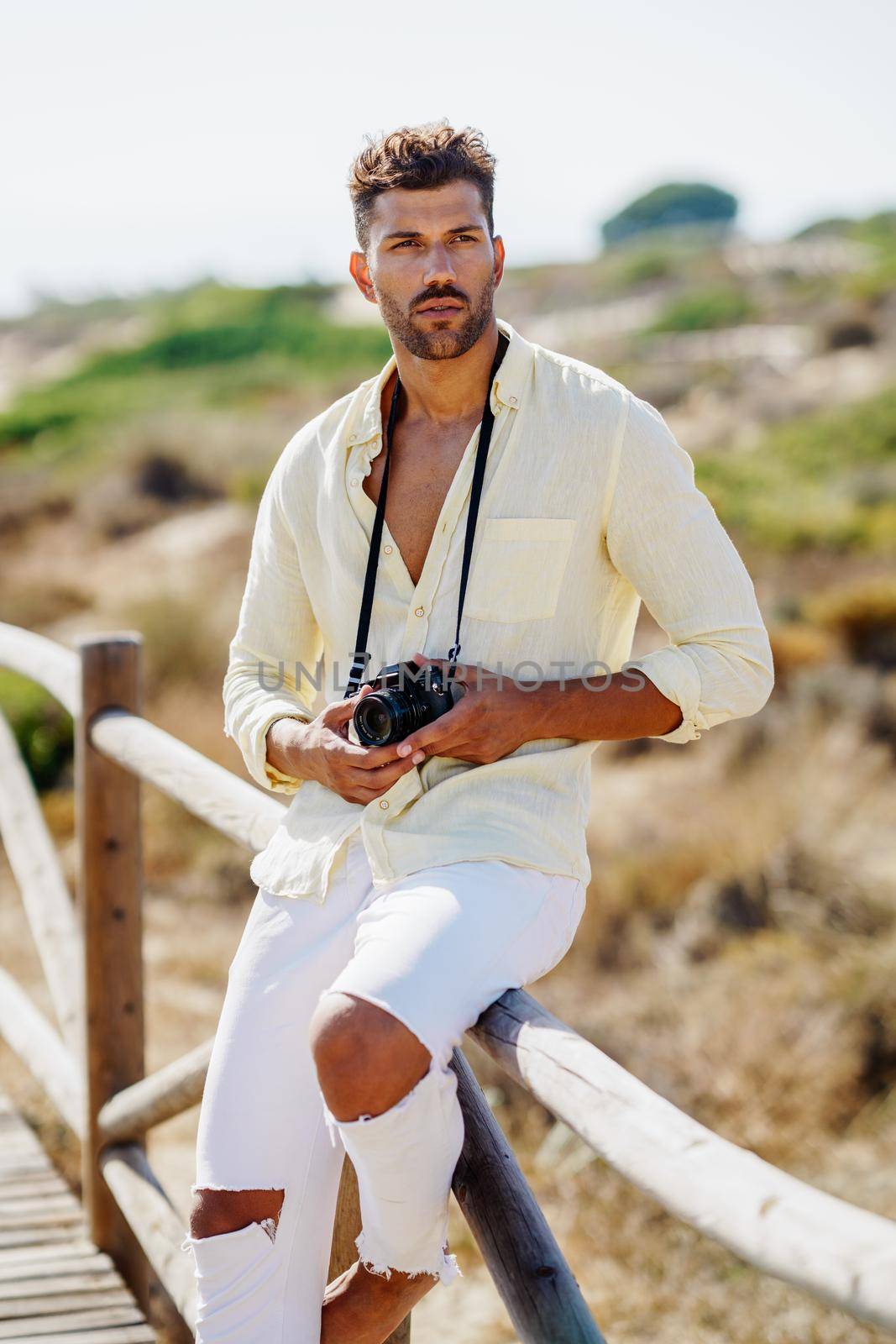 Handsome man photographing in a coastal area with an SLR camera