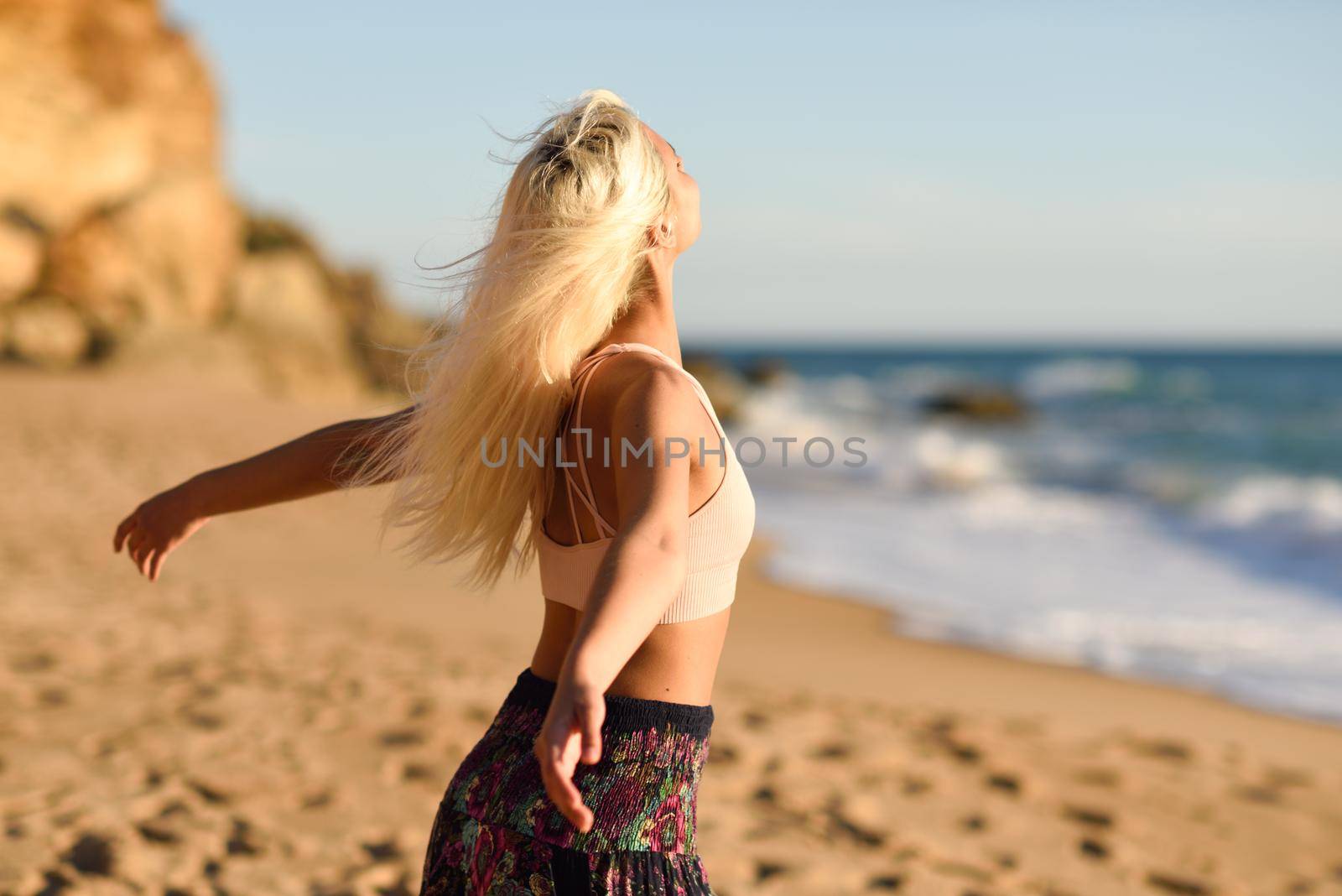 Woman enjoying the sunset on a beautiful beach in Cadiz, Andalusia, Spain. Young female opening arms and breathing the sea air.