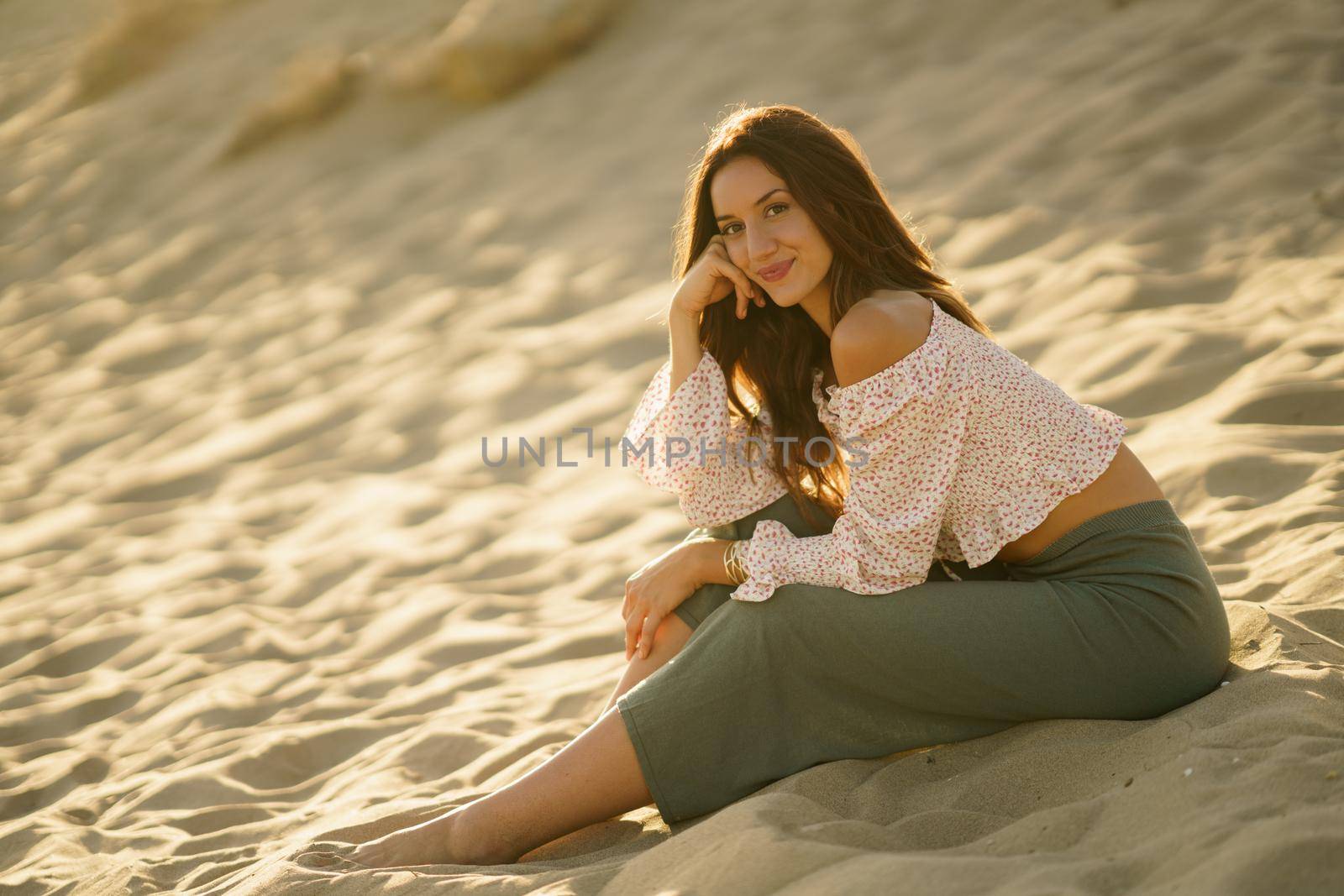 Attractive woman sitting on the sand of the beach by javiindy