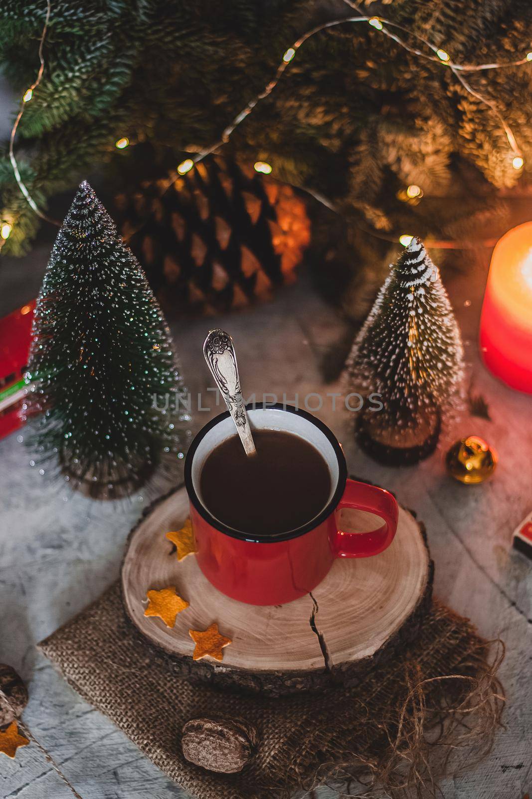 Cozy winter drink hot chocolate cocoa in red mug with fir tree, candles and Christmas lights