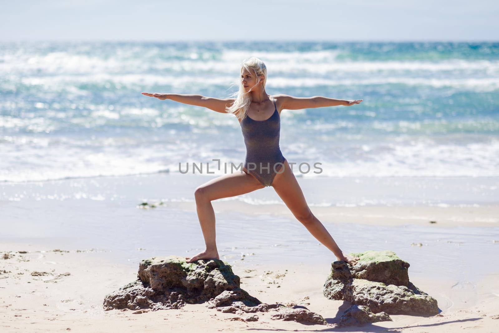 Caucasian blonde woman practicing yoga in the beach by javiindy