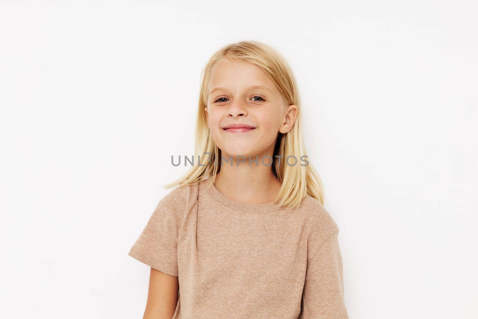 Positive little girl in a beige t-shirt on a light background. High quality photo