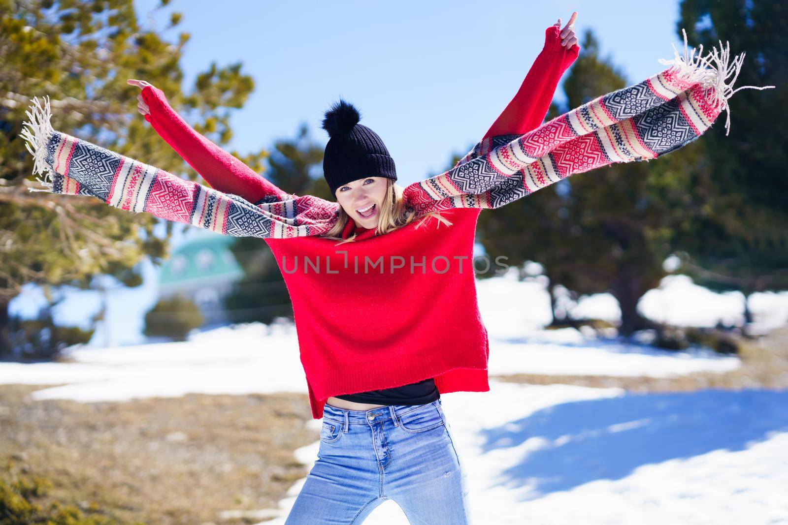 Happy young blonde woman waving her scarf in the wind in a forest in the snowy mountains in Sierra Nevada, Granada, Andalusia, Spain