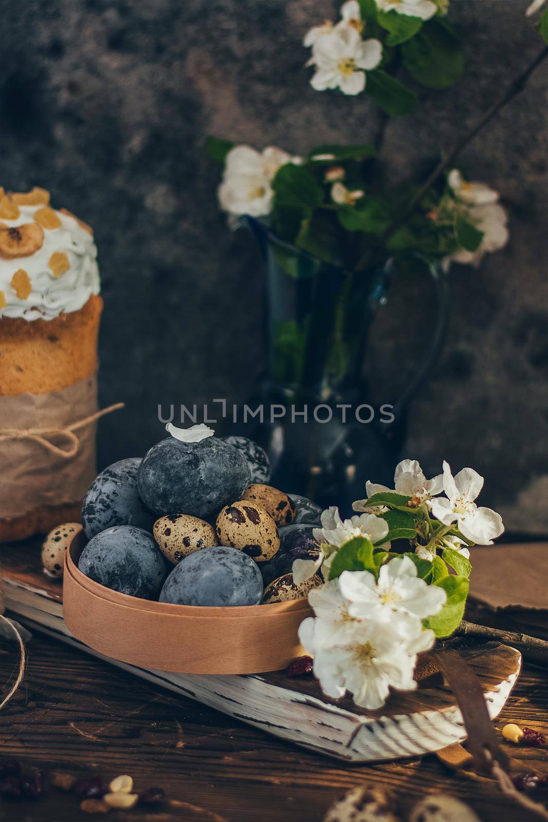 Easter eggs in the round wooden box on rustic wooden background with apple blossom branch