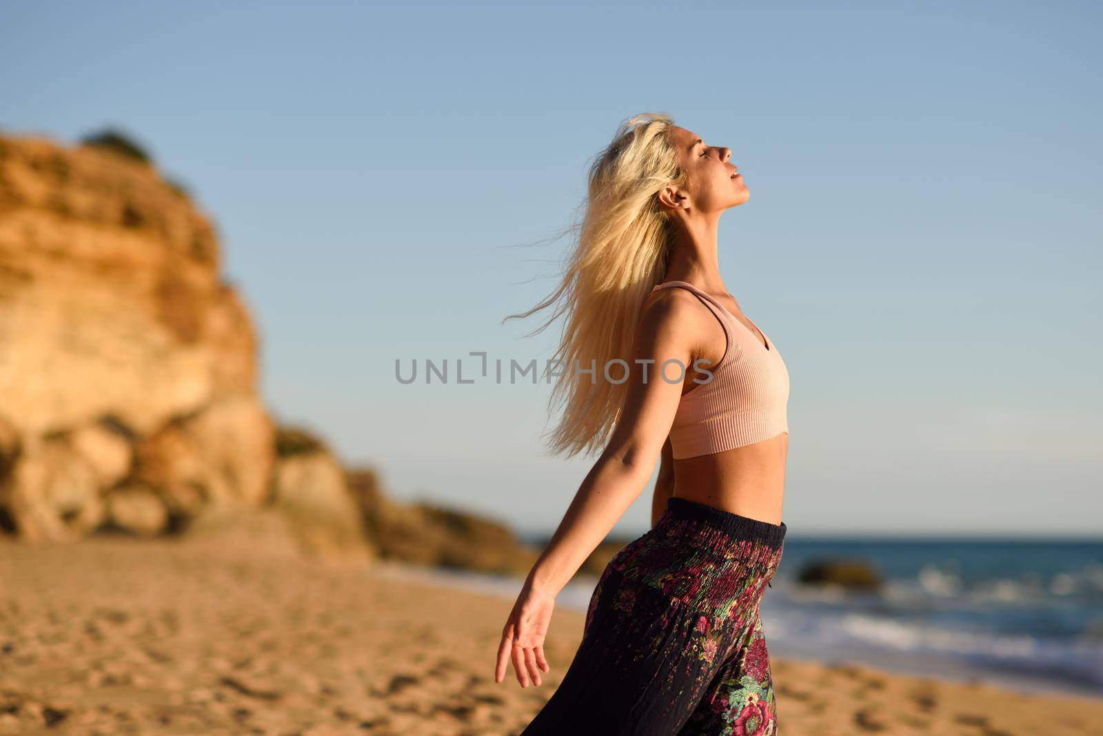 Woman enjoying the sunset on a beautiful beach in Cadiz, Andalusia, Spain. Young female opening arms and breathing the sea air.