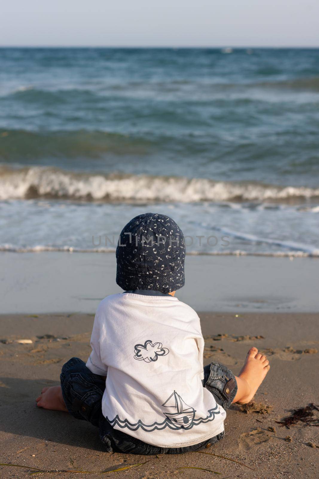 LIMASSOL, CYPRUS, Jun 19, 2010: A little boy sits for the first time on the seashore enjoying the fresh air and sea waves