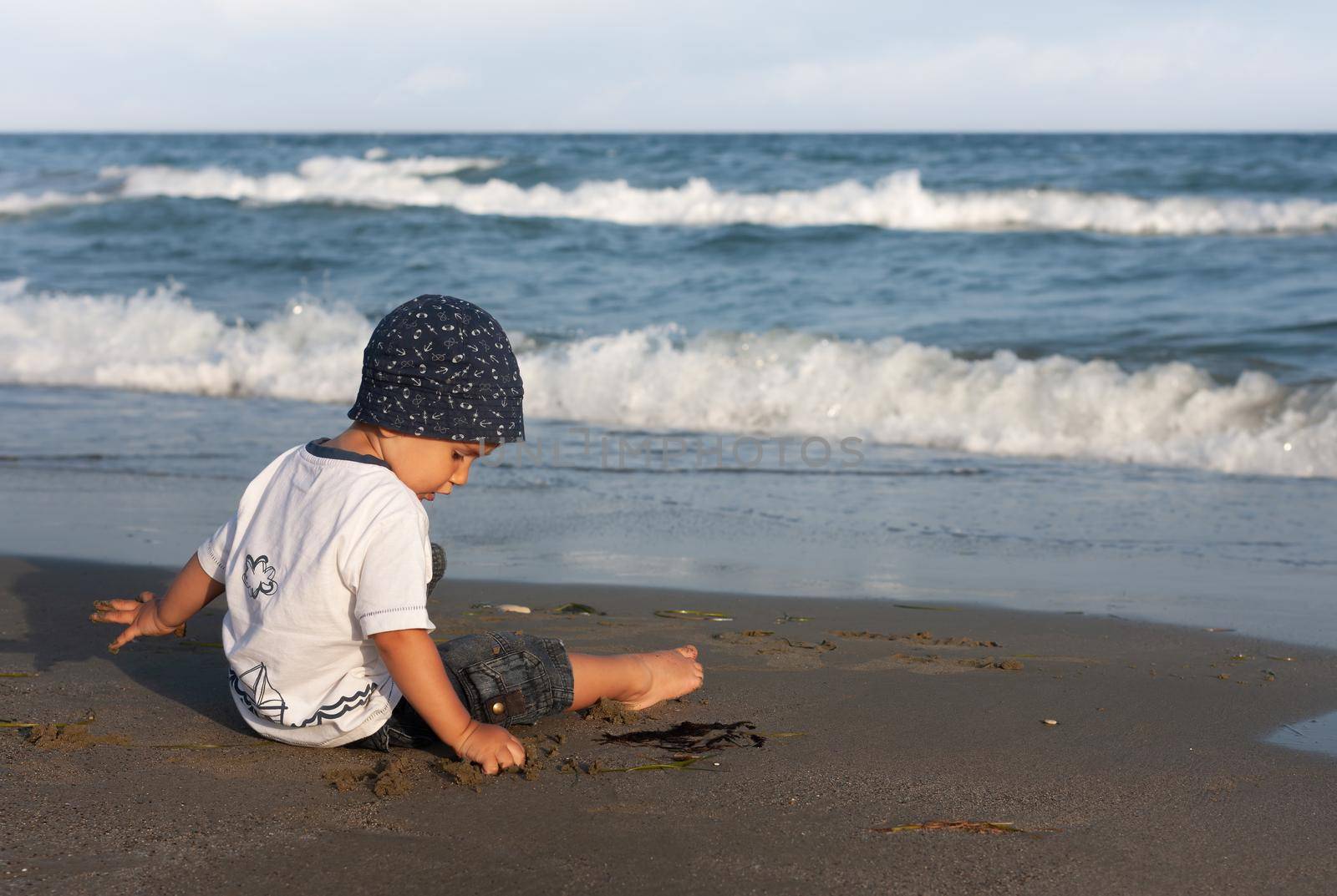 LIMASSOL, CYPRUS, Jun 19, 2010: A little boy sits for the first time on the seashore enjoying the fresh air and sea waves