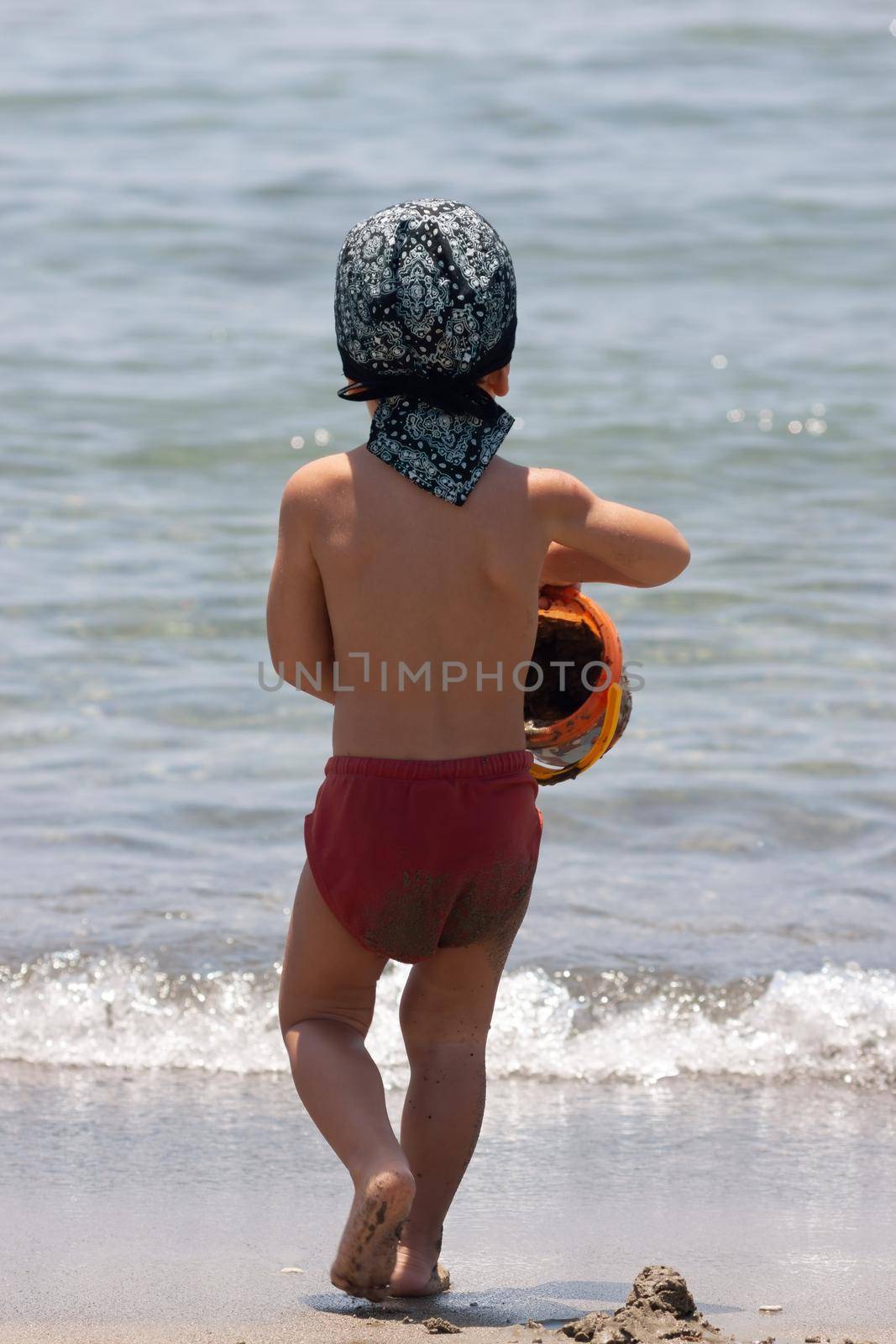 A little boy for the first time on the seashore enjoying the fresh air and sea waves