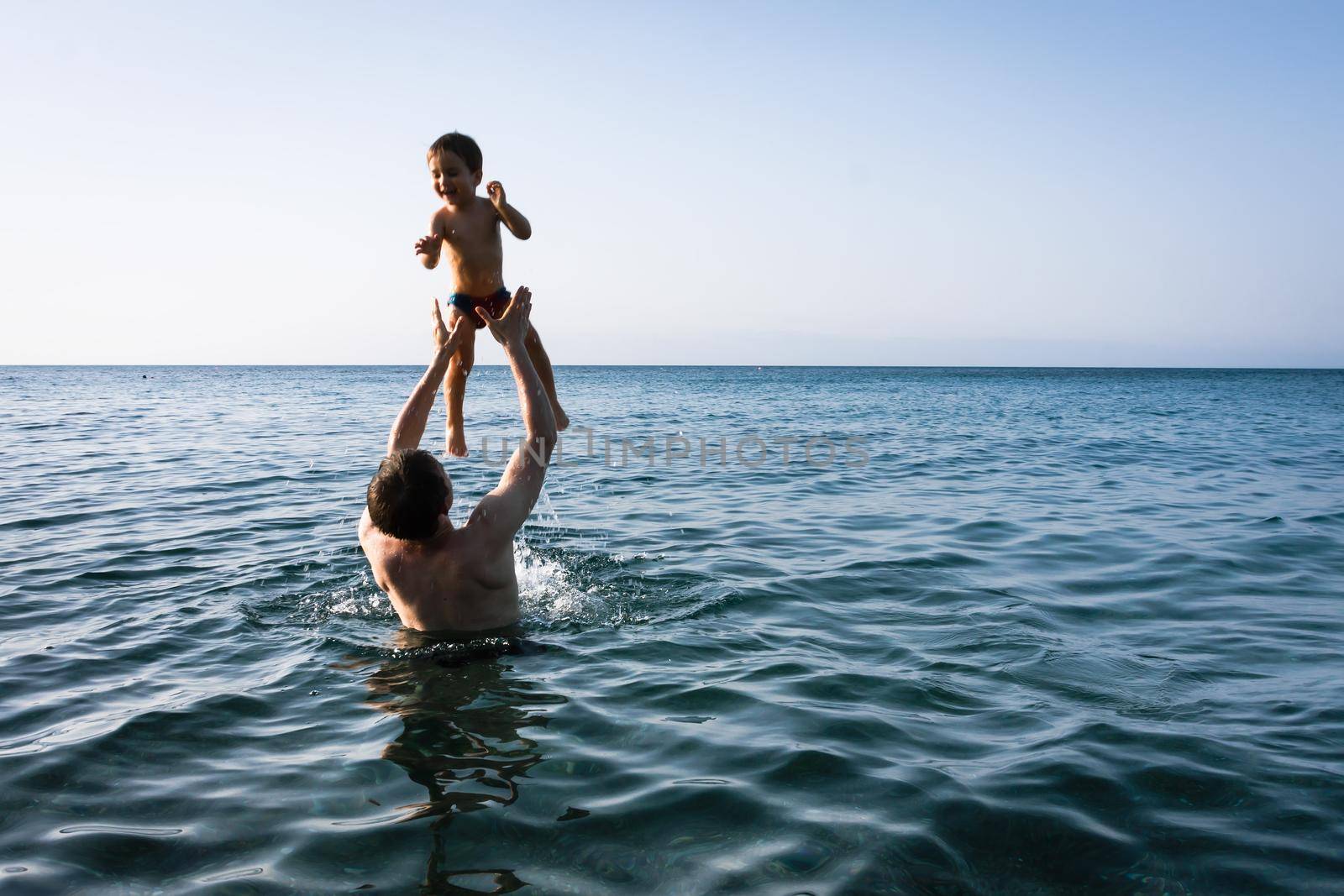 Happy family and healthy lifestyle. A young father teaches a child to swim in the sea