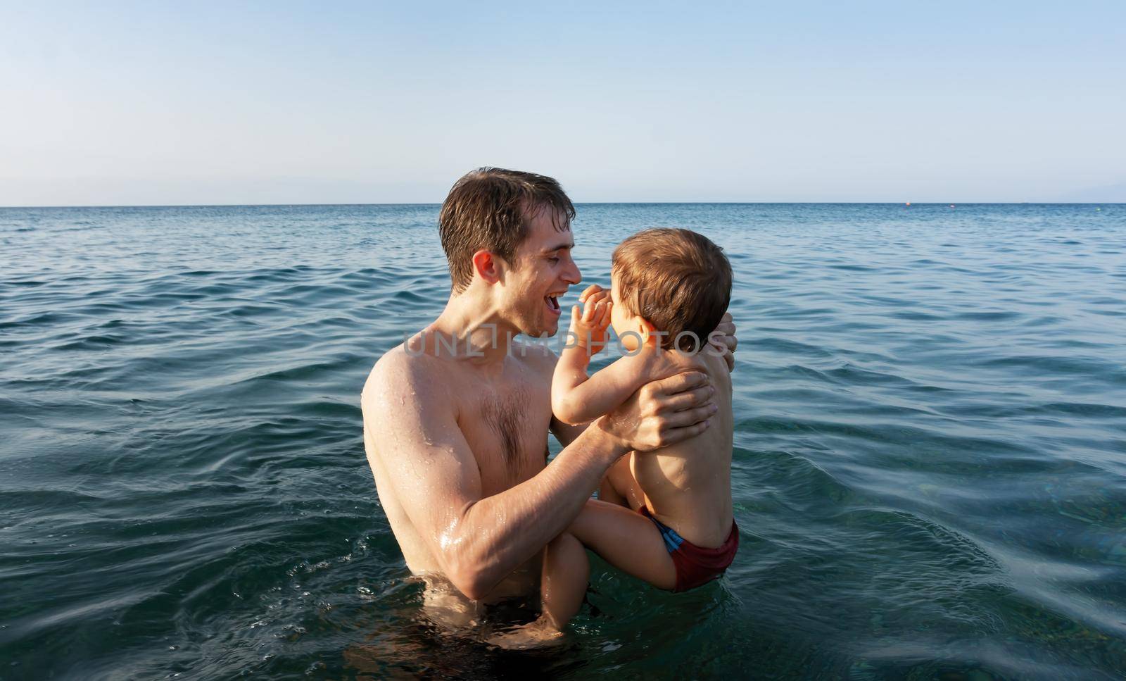 Happy family and healthy lifestyle. A young father teaches a child to swim in the sea