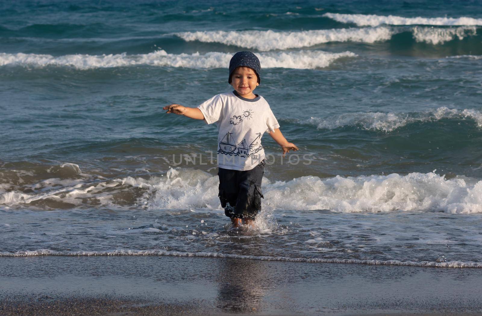 LIMASSOL, CYPRUS, Jun 19, 2010: A little boy walks for the first time along the seashore enjoying the fresh air and sea waves