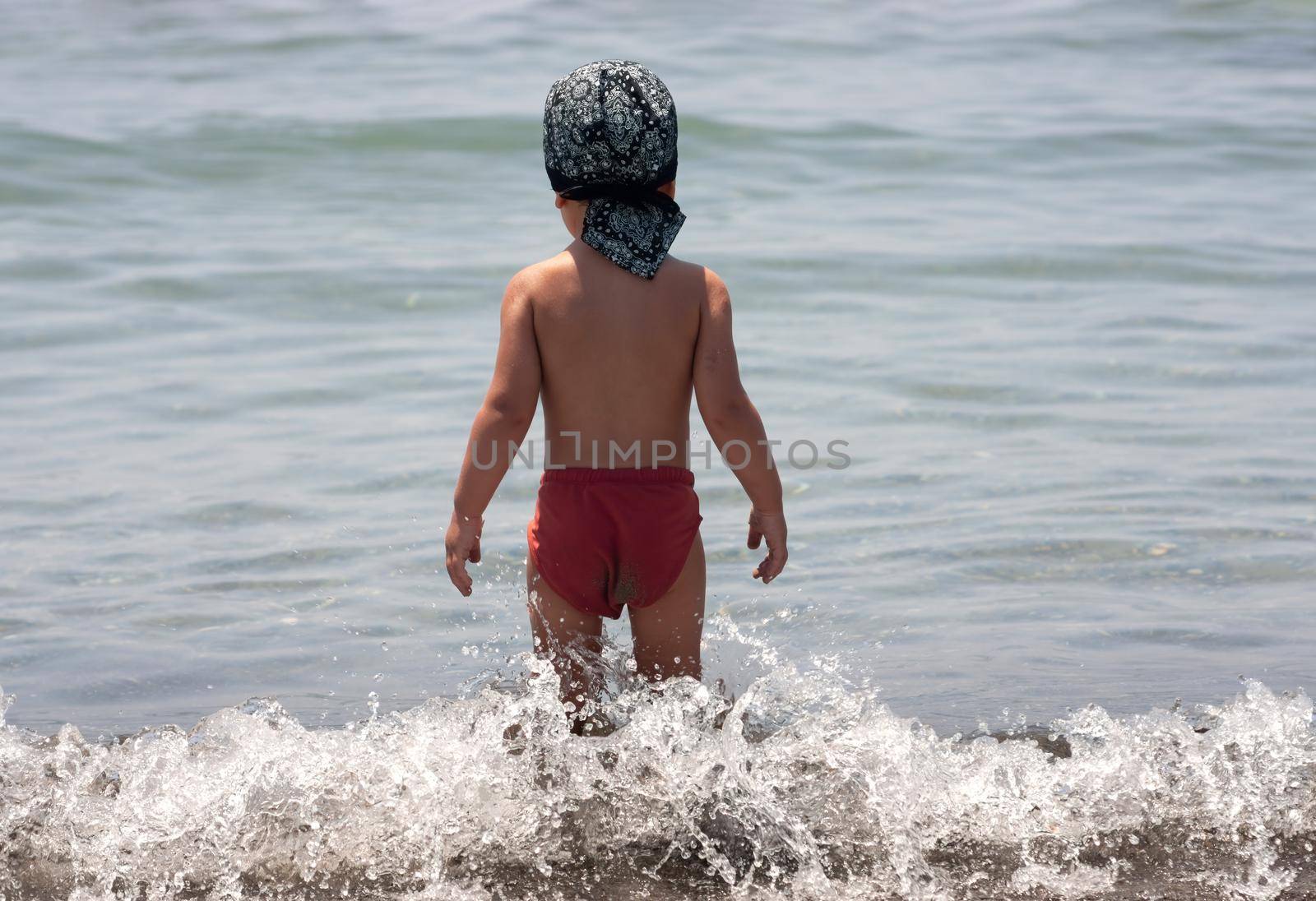 A little boy for the first time on the seashore enjoying the fresh air and sea waves