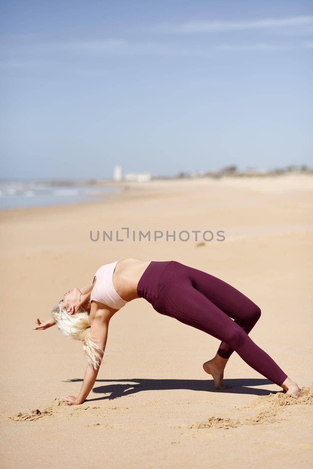 Caucasian blonde woman practicing yoga in the beach by javiindy