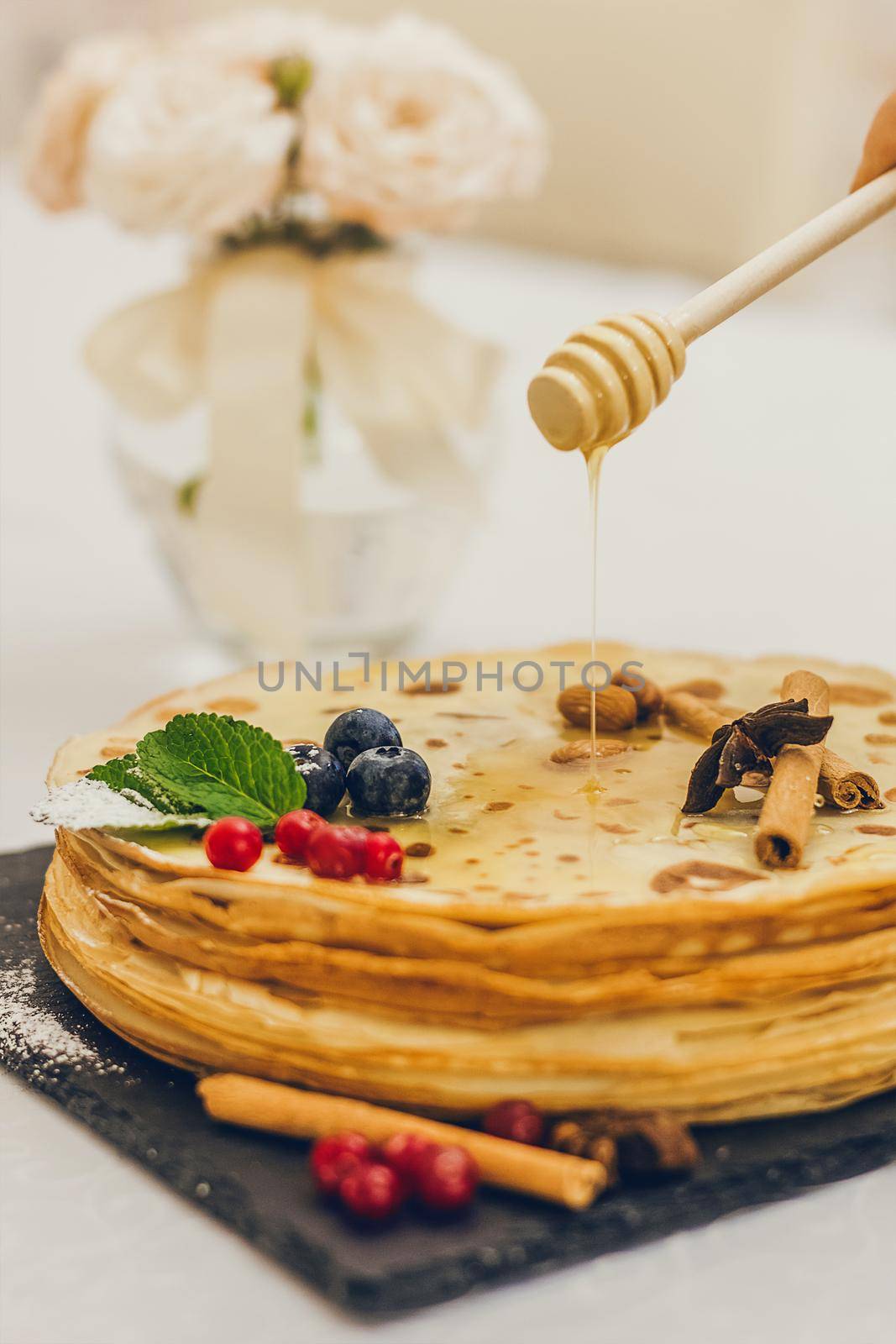 Plate of pancakes dripping with honey with cranberries and blueberries, cinnamon sticks. Shrovetide Maslenitsa Butter Week festival meal. Shrove Tuesday. Pancake day. by mmp1206