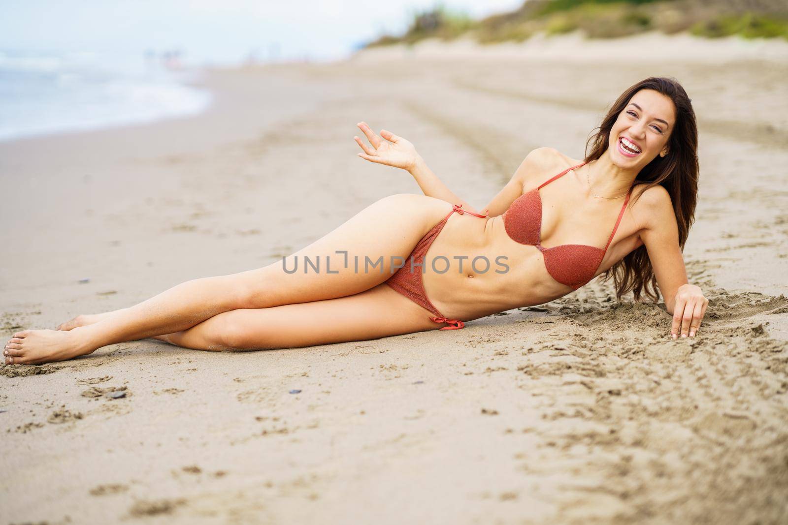 Woman with beautiful body laughing on a tropical beach wearing bikini by javiindy