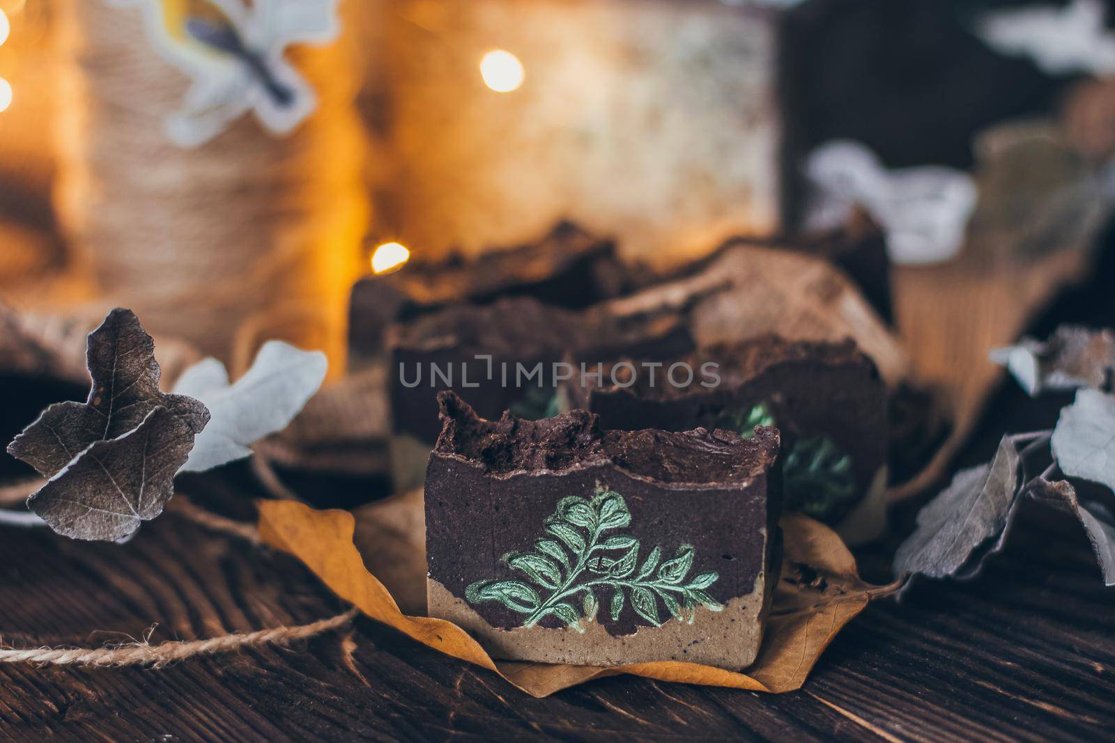 Pieces of beautiful natural handcrafted soap on wooden background with botanical elements, close up view. For relax, health, spa and aromatherapy.