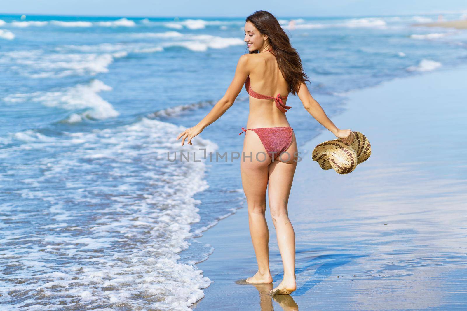 Woman in swimwear and sunhat, enjoying the beach on her holiday. by javiindy