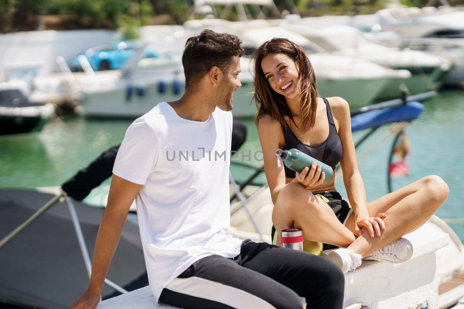 Young sporting couple hydrate themselves with water in metal cans while taking a break after sport. by javiindy