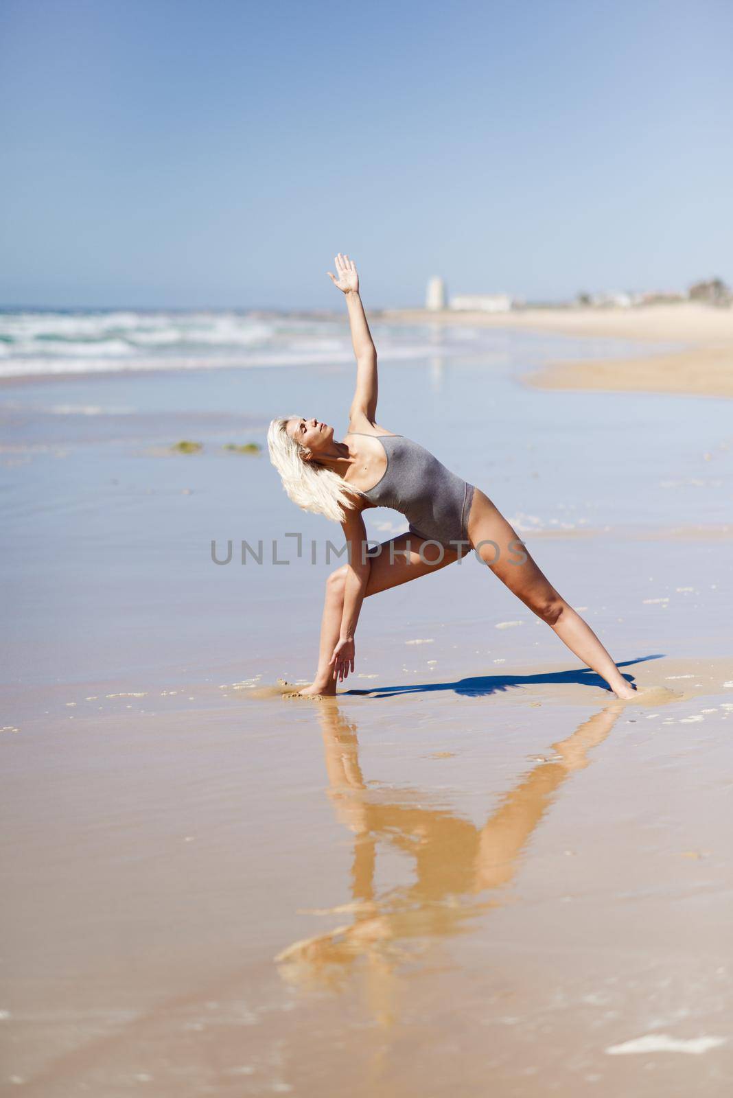 Caucasian blonde woman practicing yoga in the beach by javiindy